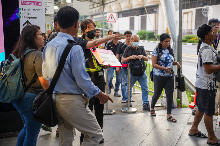 A crowd marshal giving directions to passengers. 