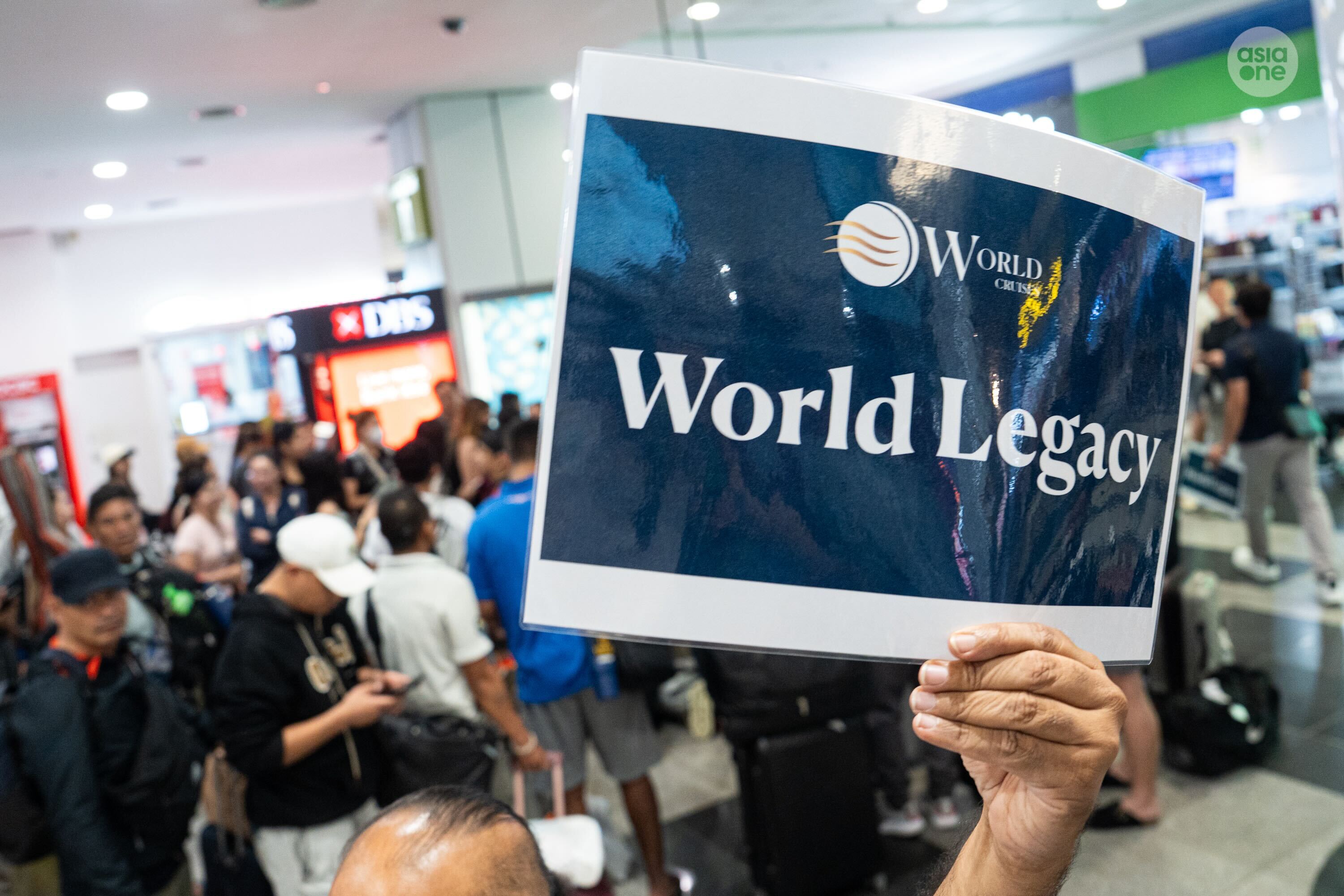 Transport workers holding up a sign for World Legacy crew members to queue for transport to a hotel. 